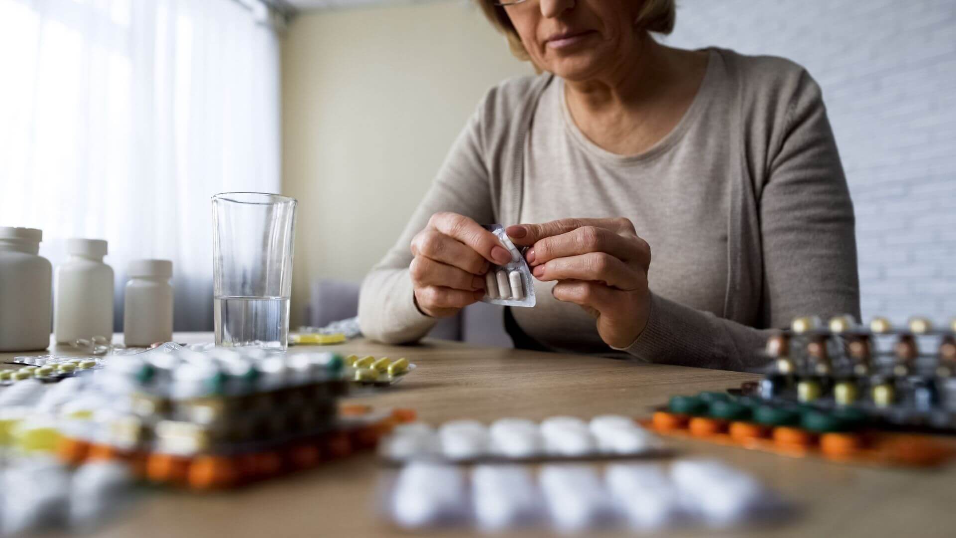 Frau mit vielen Medikamenten auf dem Tisch