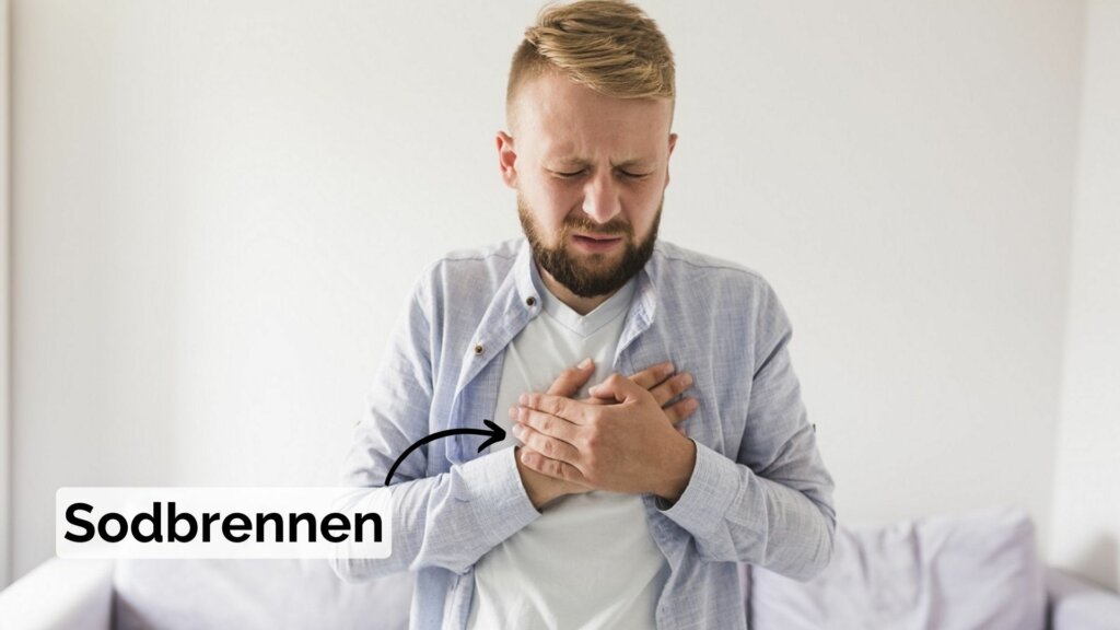 Mann hält sich die Hand vor die Brust aufgrund von Sodbrennen durch zu wenig Magensäure