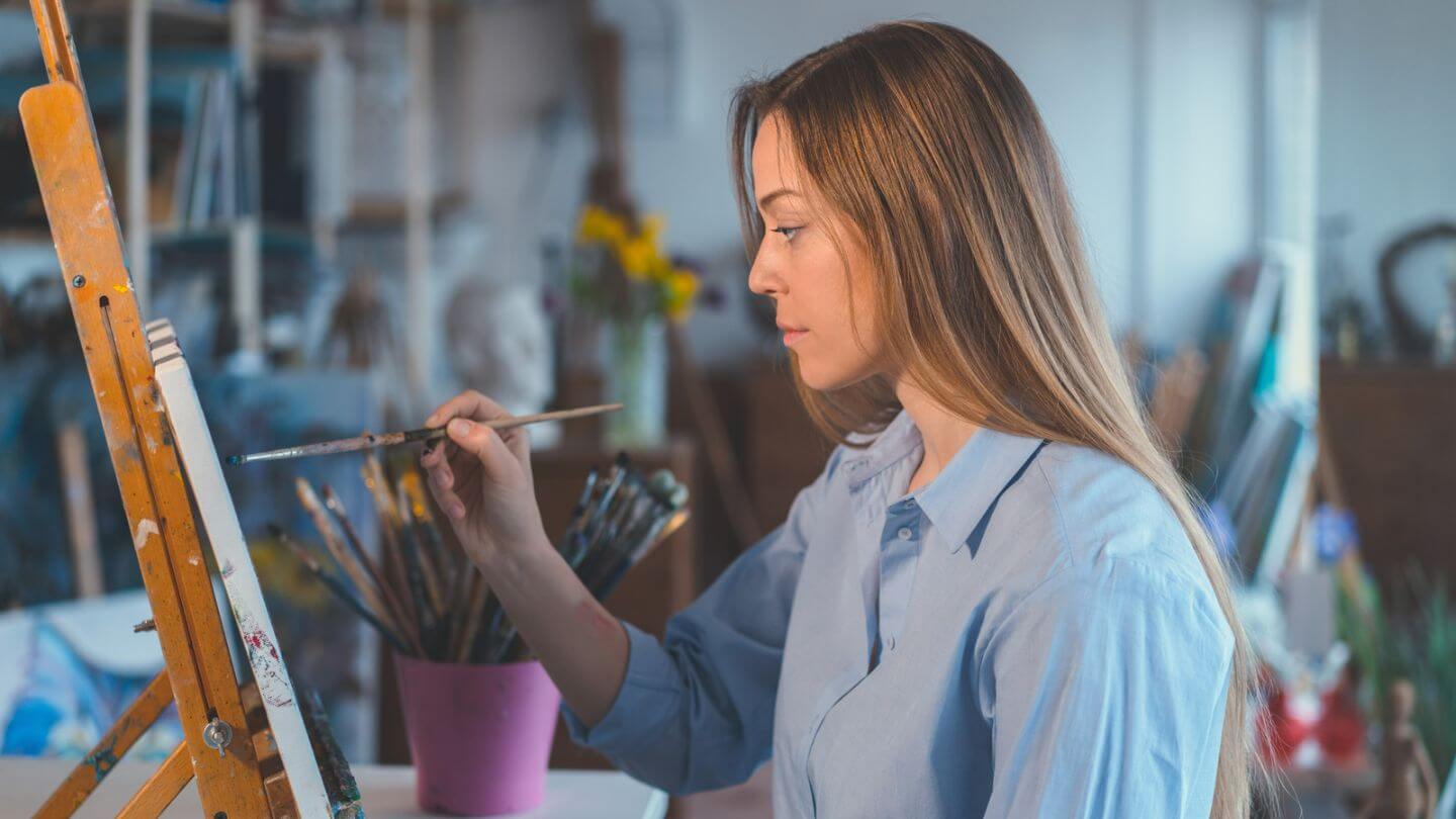 Frau malt mit Pinsel an einer Leinwand - schnelles Denken