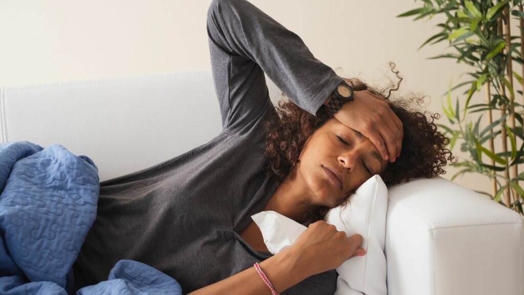 Frau liegt krank auf dem Sofa mit Krankheitssymptome