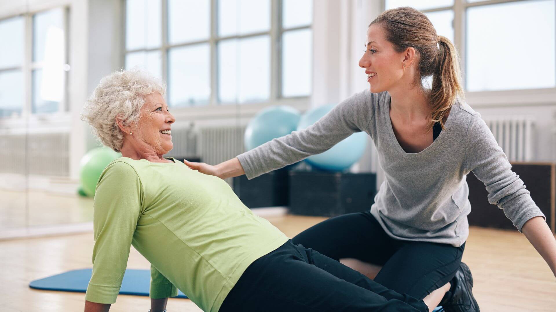 Ältere Frau mit Trainerin beim Körpertraining